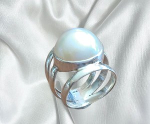 This elegant ring showcases a lustrous white mabé pearl with a smooth, radiant dome and exceptional iridescence. The pearl is securely set in polished 925 sterling silver, creating a timeless design that highlights the pearl's natural beauty. Refined and versatile, this ring adds a touch of classic sophistication to any jewelry collection.